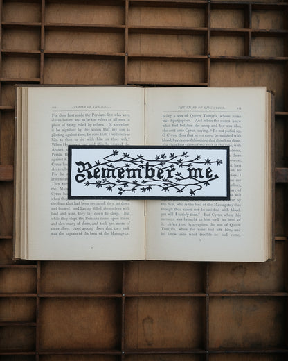 Open book with a decorative 'Remember me' bookmark on a wooden background