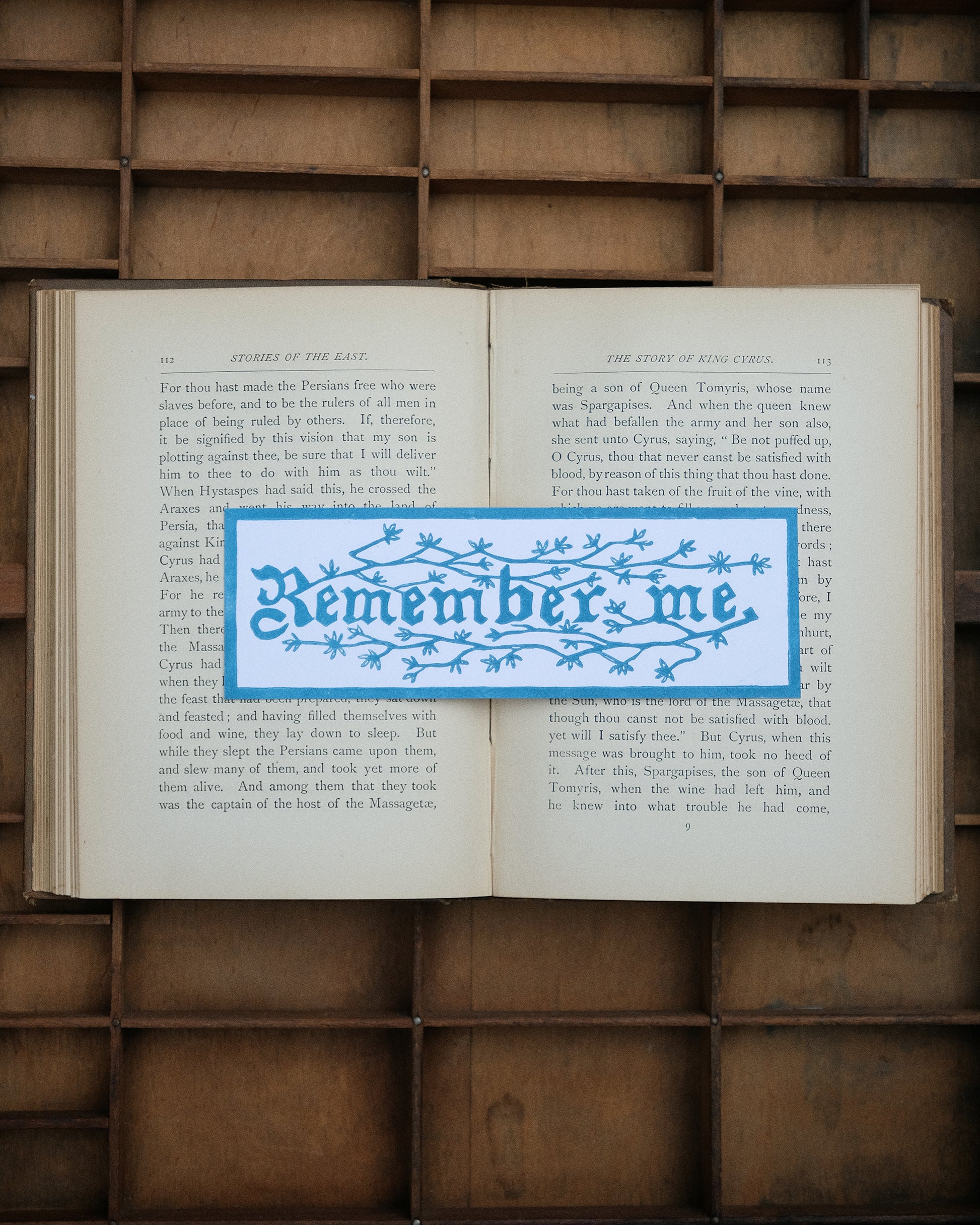 Open book with a blue 'Remember me' bookmark on a wooden background